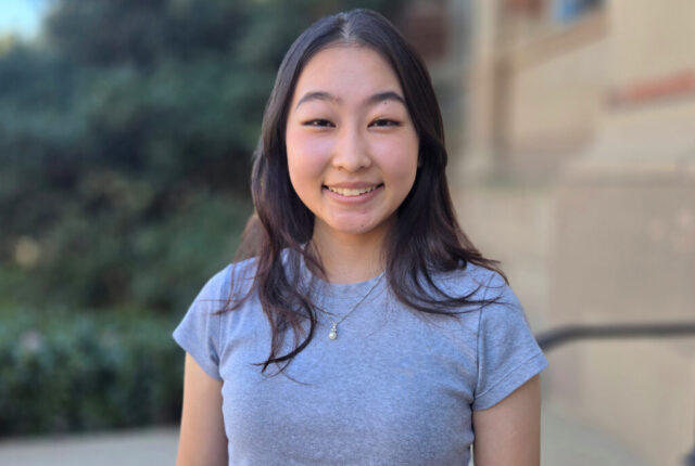 Grace Wang stands outdoors with a campus building in the background.